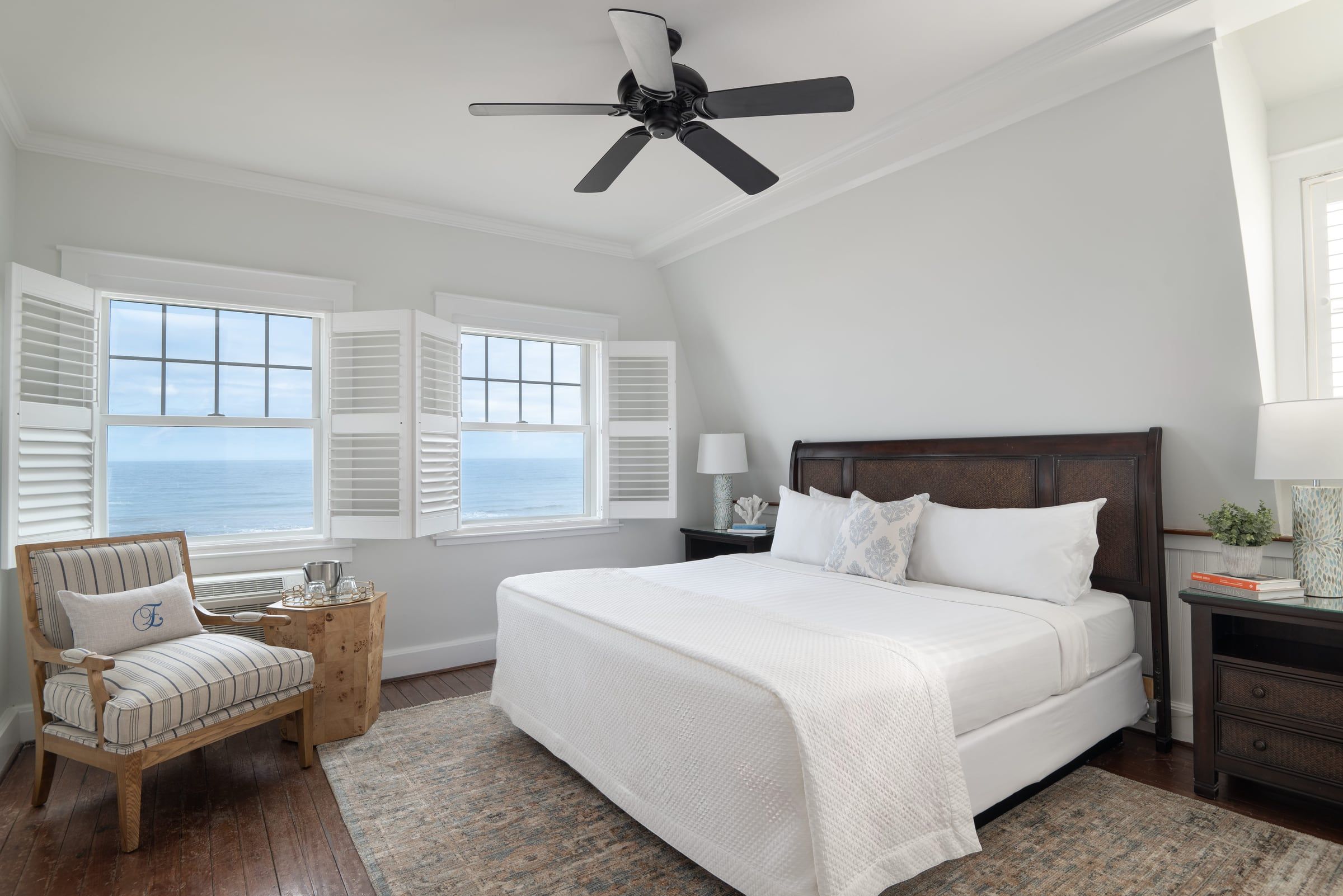 Bright Elizabeth Pointe guest room with a king bed, armchair and ocean view