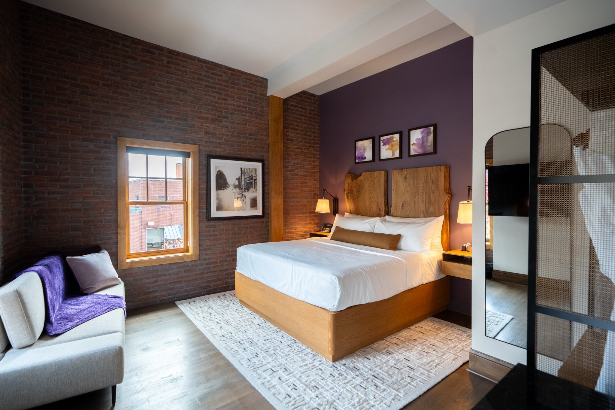 Horton Hotel guest room with purple accent wall, brick and a wood headboard